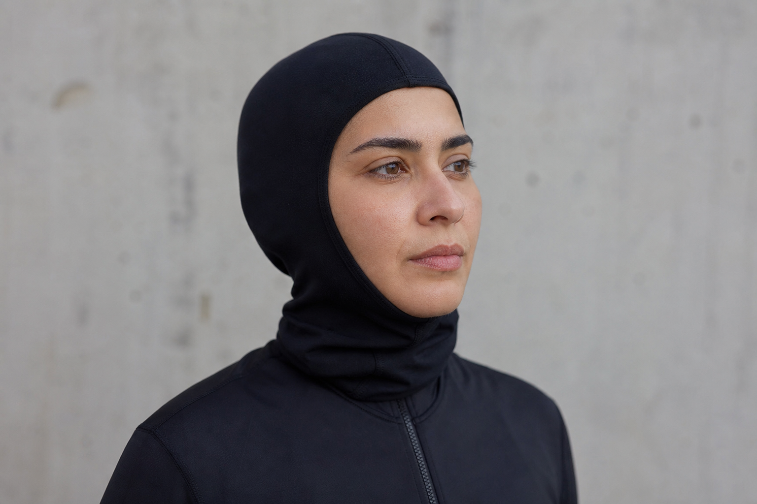 Frau trägt eine dunkle Sturmhaube und neutrale Sportkleidung bei diffusem Tageslicht